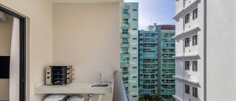 A balcony with a small sink, two air conditioning units, and a heater.