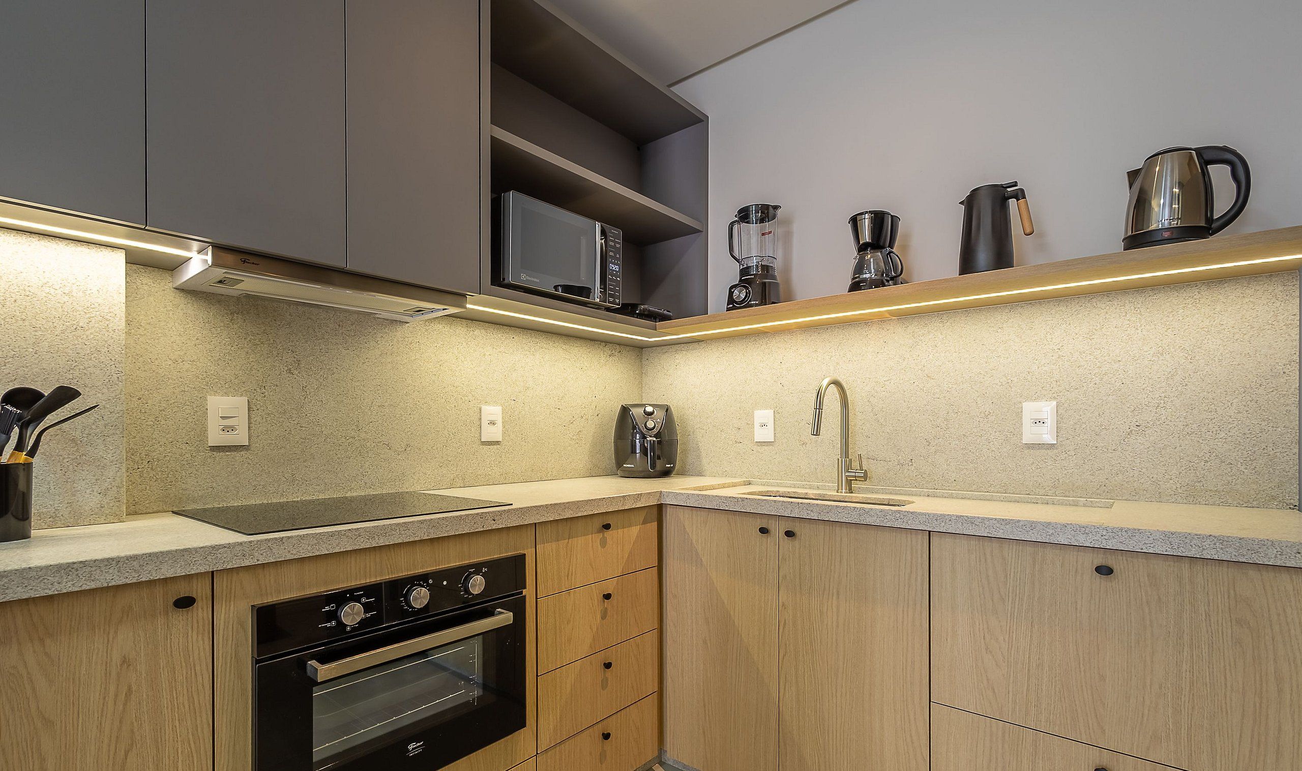 Una cocina moderna con electrodomésticos integrados, un lavamanos de acero inoxidable y armarios de madera.