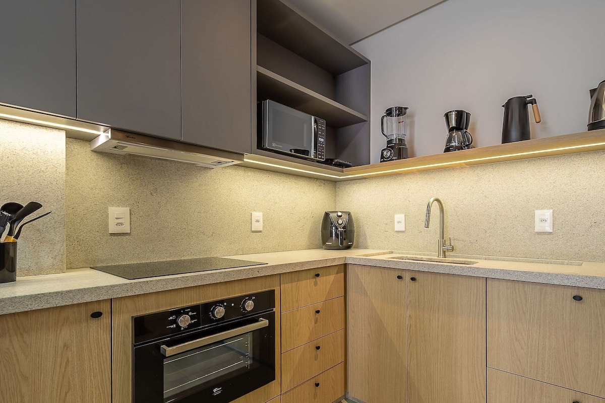 A modern kitchen with built-in appliances, a stainless steel sink, and wooden cabinetry.