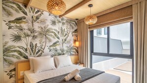 A bedroom with a large bed, tropical wallpaper, and a view of the outside. - Sua estadia exclusiva a poucos passos do Mar em Meia Praia - FFS (Itapema)