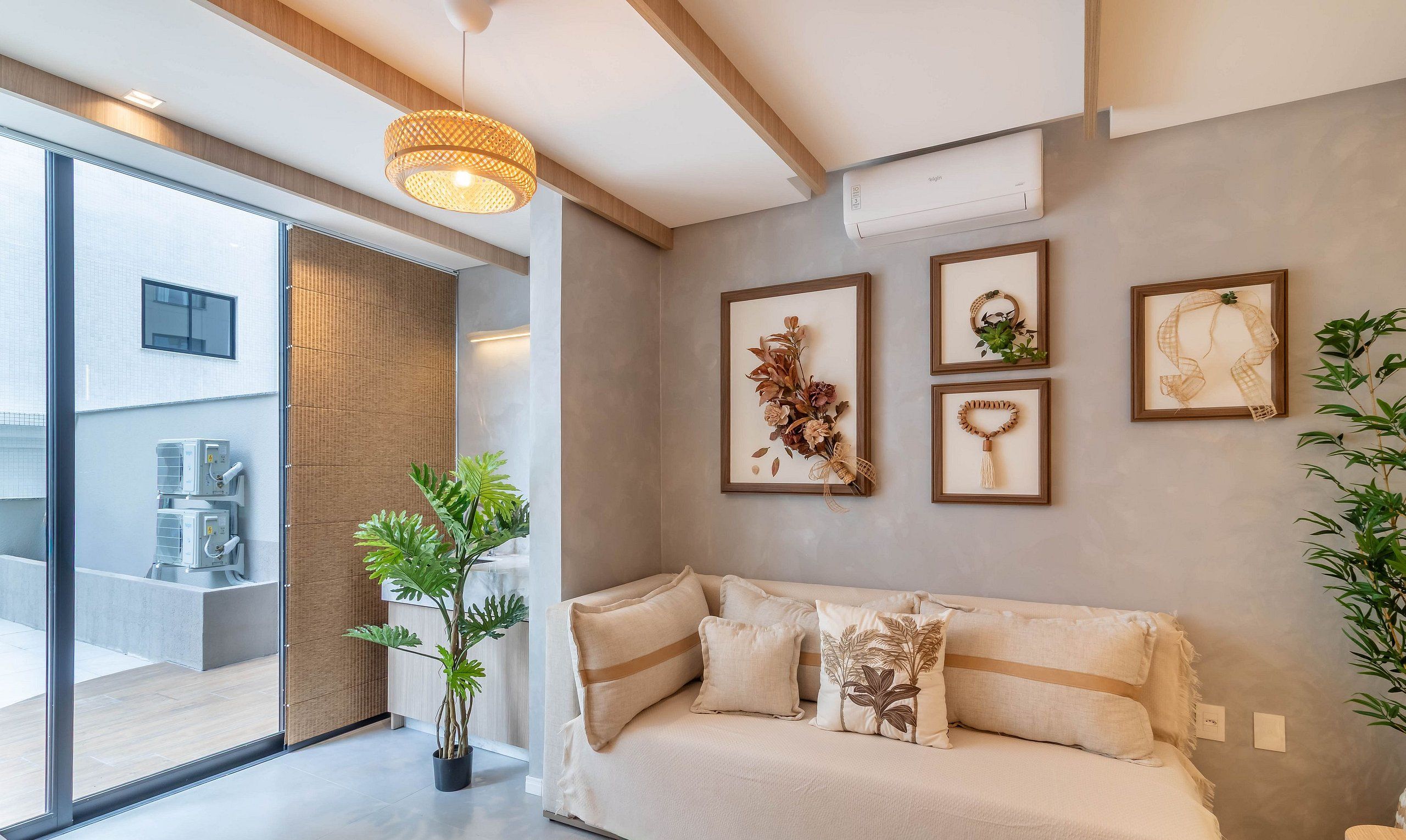 A modern living room with a sofa, a potted plant, and wall-mounted air conditioning unit.