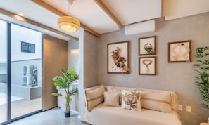 A modern living room with a sofa, a potted plant, and wall-mounted air conditioning unit. - Sua estadia exclusiva a poucos passos do Mar em Meia Praia - FFS (Itapema)
