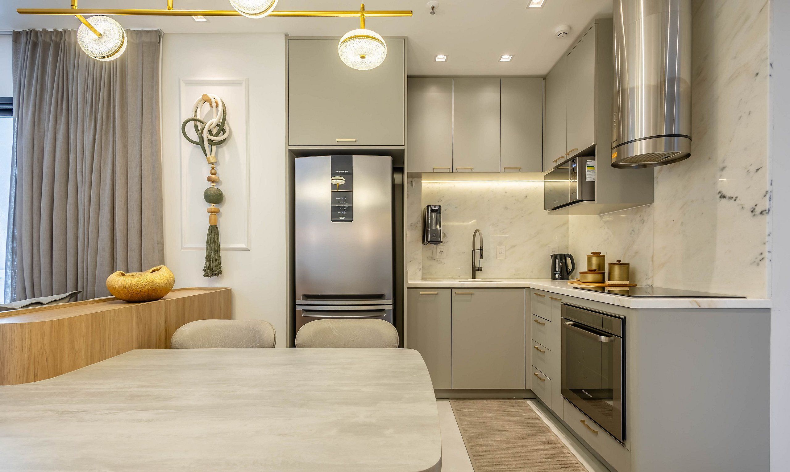 A modern kitchen with a built-in refrigerator, a stove, and a sink. There is a dining area with a table and chairs.