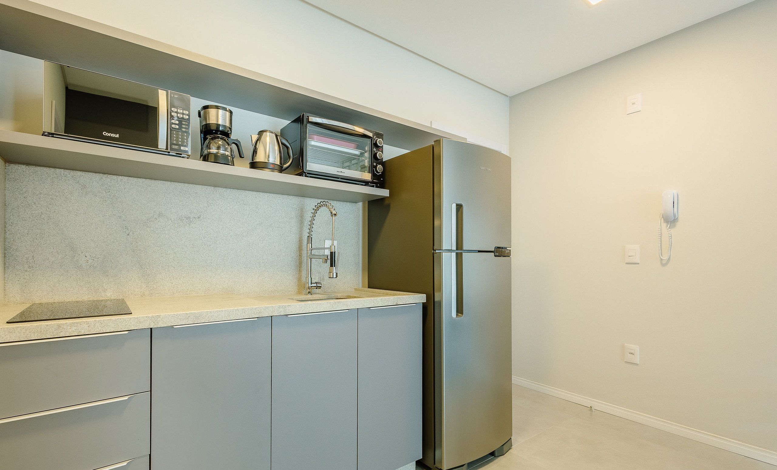 A kitchen with a built-in microwave, coffee maker, and a stainless steel refrigerator.