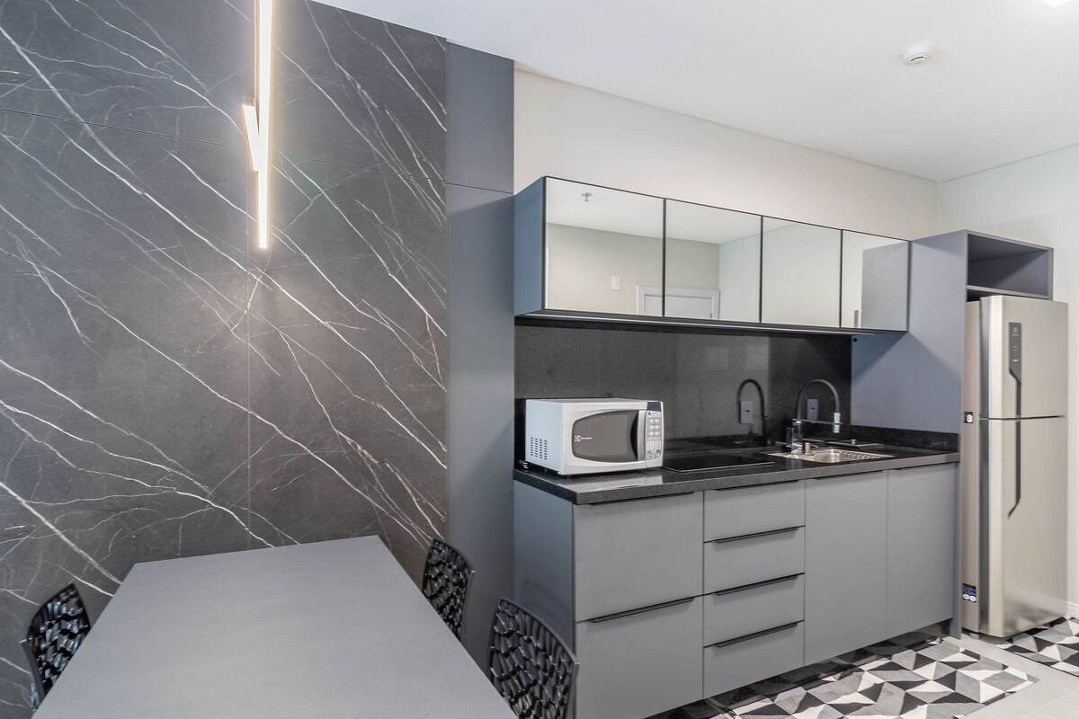 A modern kitchen with a marble backsplash, a built-in microwave, a sink, and a refrigerator.