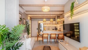 A modern kitchen with a central island, built-in appliances, and a large flat-screen TV. - Sua estadia exclusiva a poucos passos do Mar em Meia Praia - FFS (Itapema)