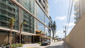Un edificio moderno con ampie vetrate, un'auto parcheggiata e cielo sereno.