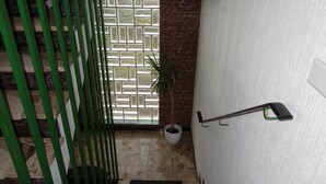 A staircase with a green metal railing, a potted plant, and a white wall with a textured pattern. - Charming Apartment in Quiet Ubbedissen (Bielefeld)