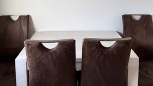 A dining area with a white table and two brown upholstered chairs. - Charming Apartment in Quiet Ubbedissen (Bielefeld)