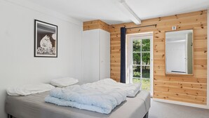 A bedroom with a bed, a window, wooden paneling, and a framed picture on the wall. - Holiday on lovely nature plot for families (Hadsund)