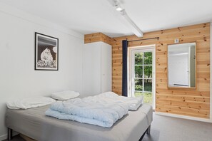 A bedroom with a bed, a window, wooden paneling, and a framed picture on the wall. - Holiday on lovely nature plot for families (Hadsund)