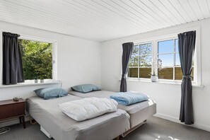 Ein Schlafzimmer mit zwei Betten, einem Schreibtisch und zwei Fenstern mit Vorhängen.