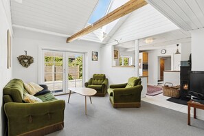 Een gezellige woonkamer met een bank, fauteuils, een televisie en een open haard.