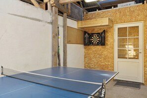A ping pong table, a dartboard, and a door with glass panels.