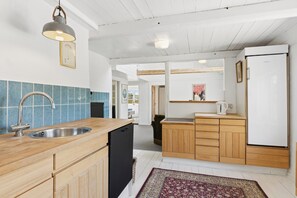 Eine moderne Küche mit Holzschränken, einer Edelstahlspüle und einem Kühlschrank.