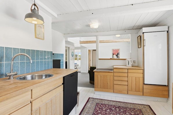 A modern kitchen with wooden cabinets, a stainless steel sink, and a refrigerator.
