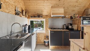 A modern kitchen with a wooden ceiling, built-in appliances, and a large window. - Holiday on lovely nature plot for families (Hadsund)