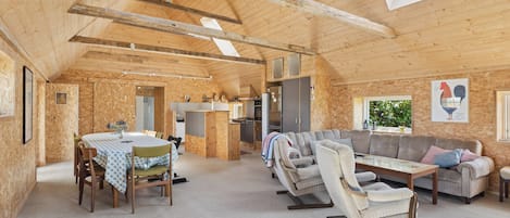 A wooden interior with a dining area, sofa, and rocking chairs.