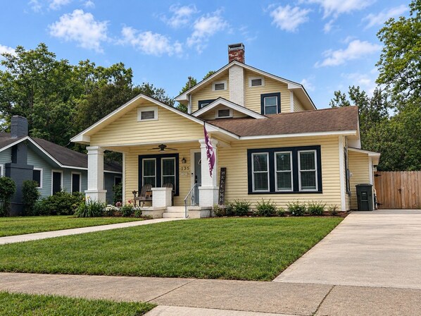 A two-story house with a front porch, a flag, and a number '135' on the door.