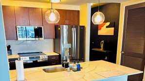 Cocina moderna con una isla central, electrodomésticos de acero inoxidable e iluminación colgante.