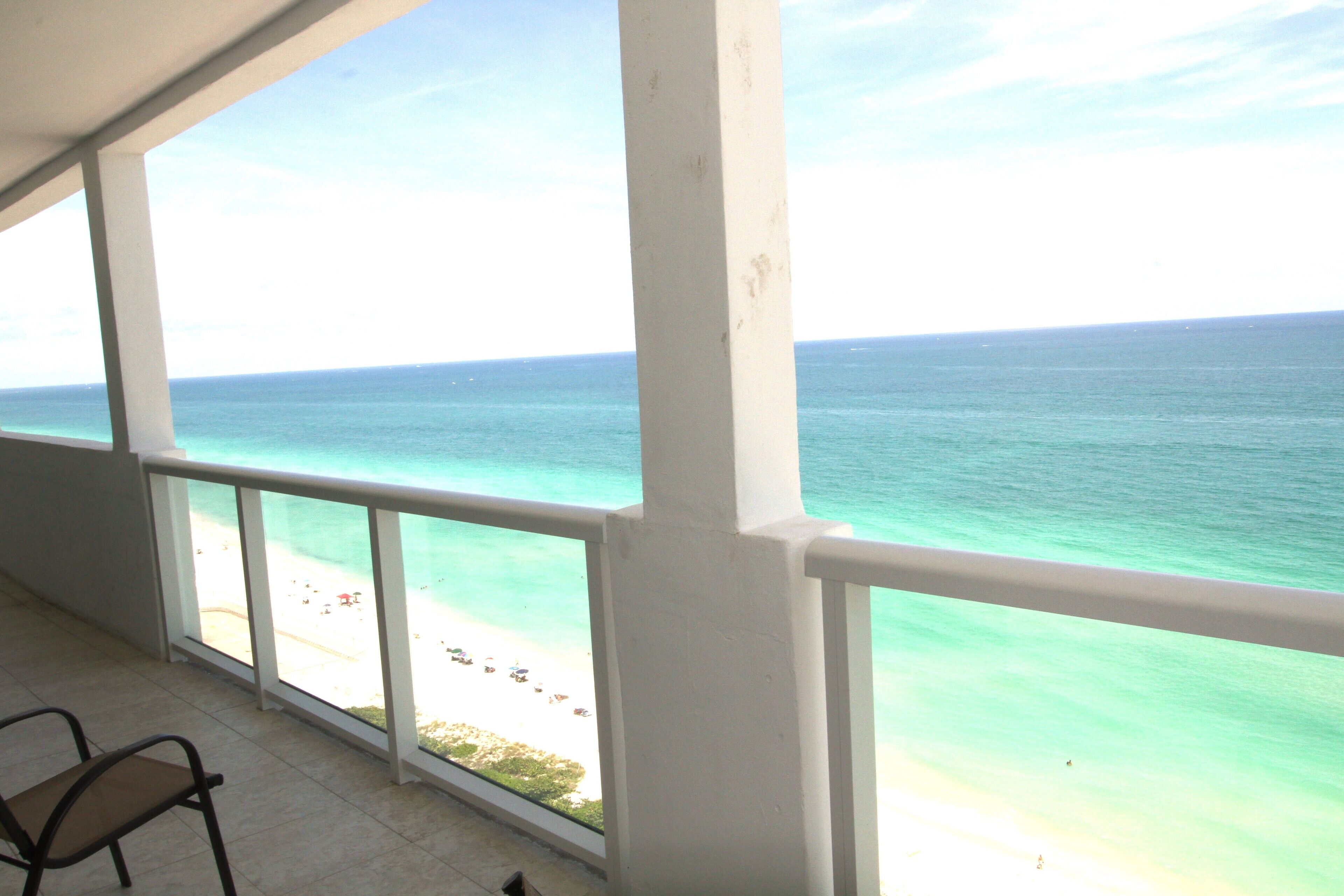 A balcony with a view of the ocean and beach.