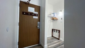 Un couloir avec une porte en bois, un porte-manteau et une pile de serviettes pliées.