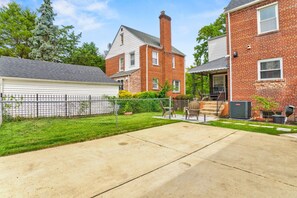 A residential property with a covered patio, a brick house, and a fenced yard.