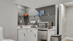 Een compacte kitchenette met een magnetron, een kleine koelkast en een afvalbak.
