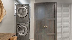 Een wasserette met gestapelde wasmachines, een houten garderobe en een witte kast.