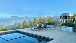 A modern outdoor pool area with lounge chairs and a view of mountains.