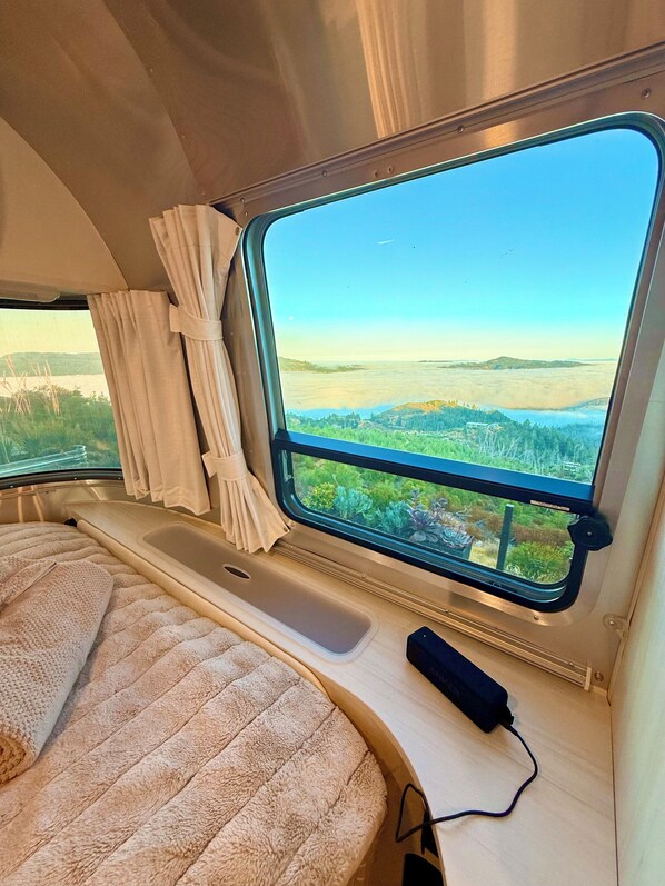 Un interior acogedor con una cama, una ventana con cortinas y vistas a un paisaje.