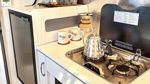 A compact kitchenette with a stainless steel refrigerator, a coffee maker, and a sink.