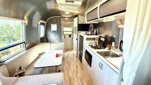 A compact RV interior with a kitchenette, a dining area, and a seating space.