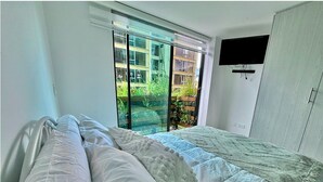 Une chambre à coucher avec un lit, une fenêtre et un téléviseur fixé au mur.