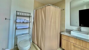 A bathroom with a toilet, a shower curtain, a towel rack with towels, a sink, and a mirror. - Luxury 2BR + Gym & City Views| Near Spain Embassy (QUITO)