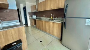 A modern kitchen with wooden cabinets, a stainless steel refrigerator, and a granite countertop. - Luxury 2BR + Gym & City Views| Near Spain Embassy (QUITO)