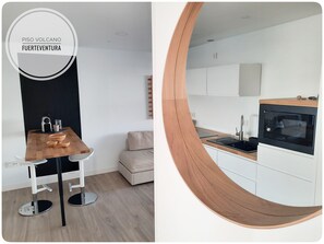 Een moderne keuken met een magnetron, spoelbak en een houten aanrecht.