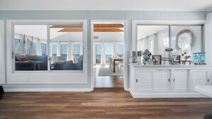 Une pièce spacieuse dotée de grandes fenêtres, d’un plancher en bois, d’un coin repas et d’un espace cuisine agrémenté d’objets décoratifs.