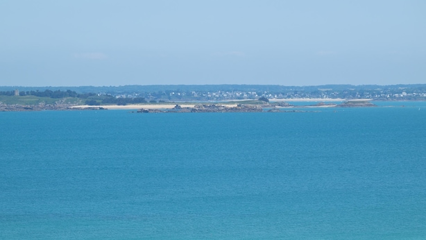 Vista costera con playa y un pueblo distante.