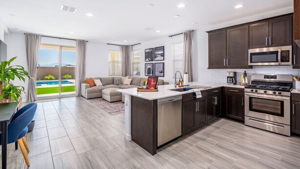 A modern kitchen with dark cabinets, stainless steel appliances, and a large island.