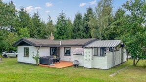 Een gelijkvloers huis met een terras, een barbecueplek en een auto in de buurt.