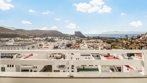Un pueblo costero con edificios blancos, una destacada formación rocosa y vistas al mar.