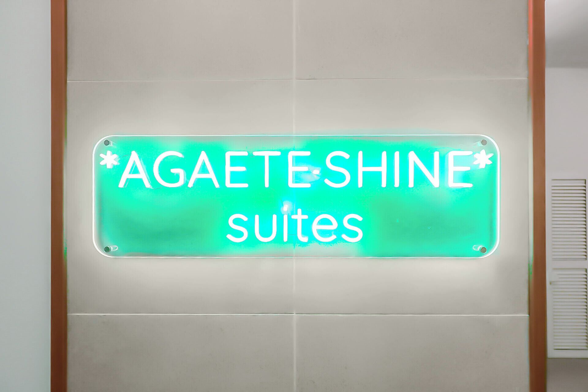 Un letrero de neón con el texto "AGAETESHINE suites" en una pared.