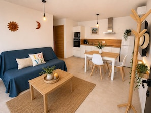 A modern kitchen with white cabinets, a wooden dining table, and a blue sofa with a 'LOVE' pillow.