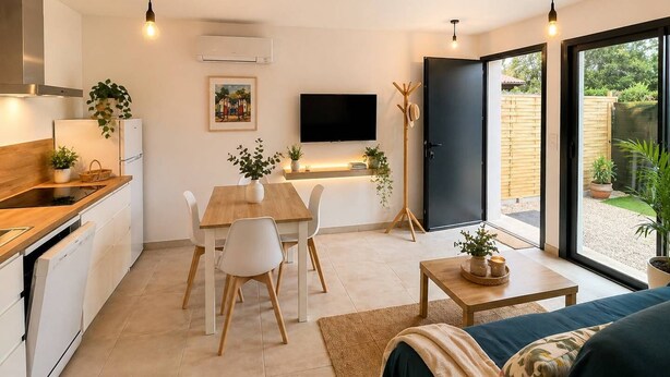 A compact kitchen with a dining area, a flat-screen TV, and a sliding glass door leading to a garden.