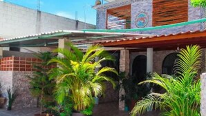 A residential building with a covered patio area, potted plants, and a clear blue sky. - Hotel Vías Maya Bacalar - Free Bikes (Bacalar)