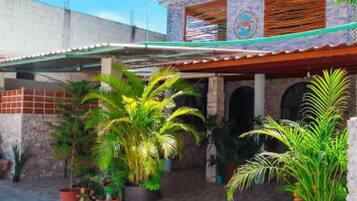A residential building with a covered patio area, potted plants, and a clear blue sky.