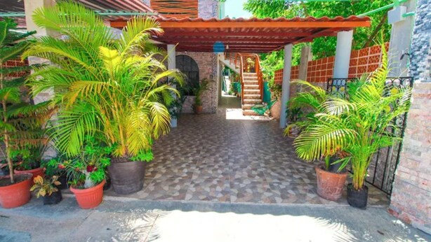 A covered patio area with tiled flooring, potted plants, and a staircase leading to an upper level. - Hotel Vías Maya Bacalar - Free Bikes (Bacalar)