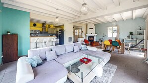 A modern living room with a sectional sofa, a glass coffee table, and a dining area with colorful chairs. - Belle Maison vue montagnes (Bidarray)