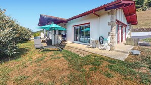 A modern house with a red roof, a patio with a blue umbrella, and a stone pillar. - Belle Maison vue montagnes (Bidarray)